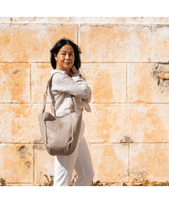 Bolso multi posición con bolsillos exteriores, asas cortas y correa larga regulable. Piel color topo